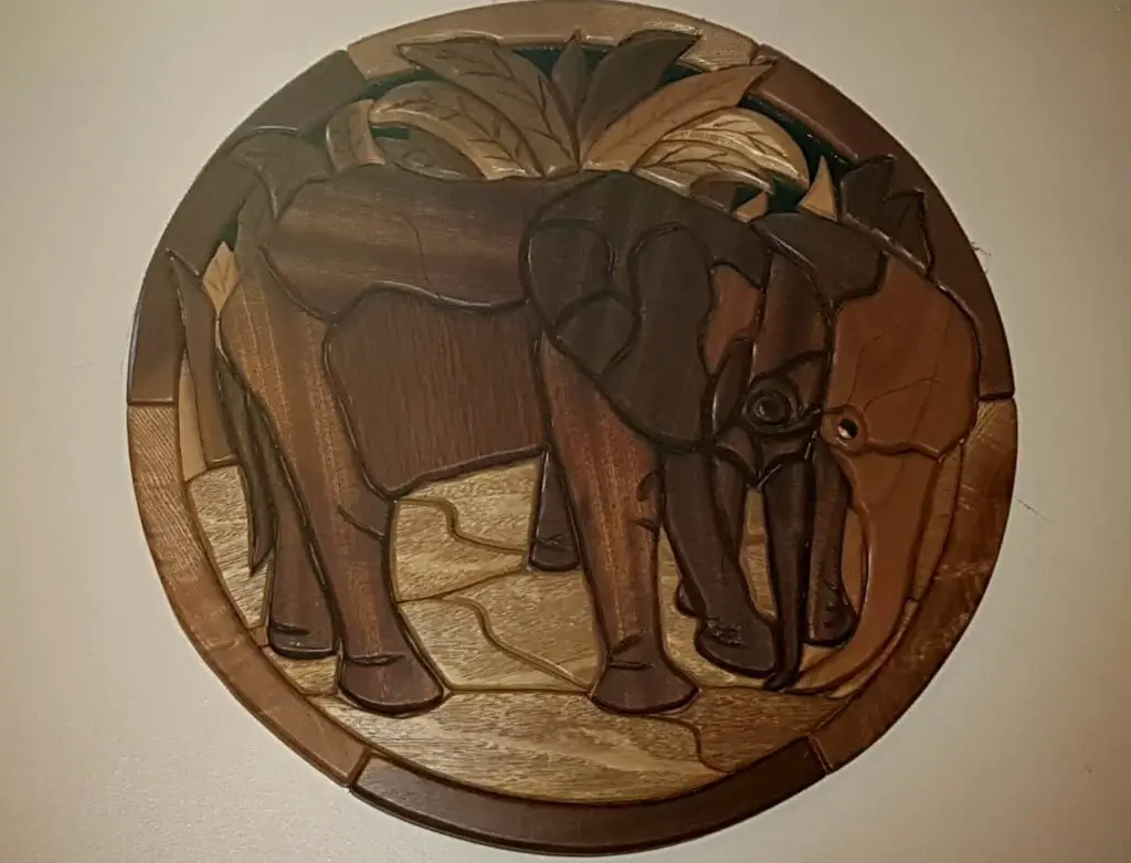 round intarsia picture of two elephants with foliage background