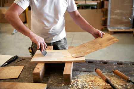 Carpenter applying glue to attach briar root panel