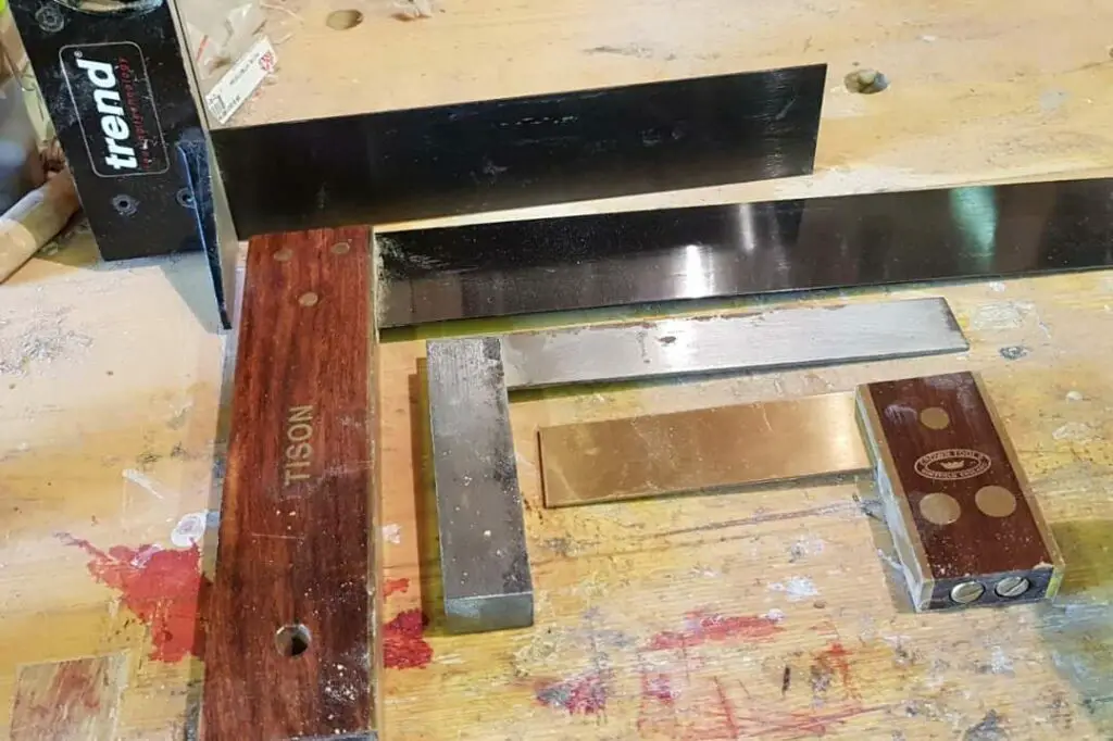 four woodworking try squares on workbench